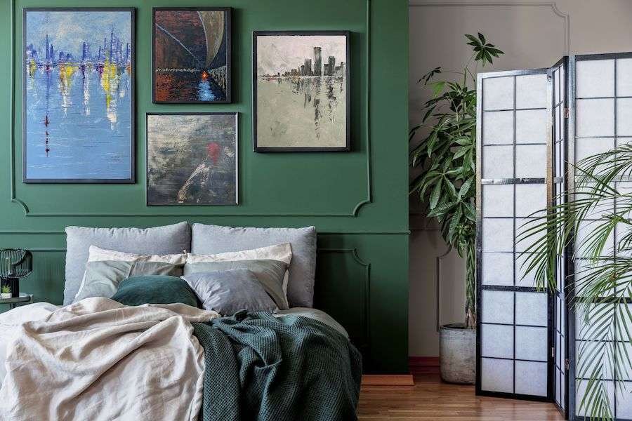 green bedroom featuring 4 large framed paintings arranged on one wall in a collage style
