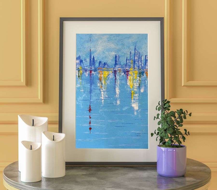 A vignette of a framed painting, with a small plant on one side and three candles on the other side.